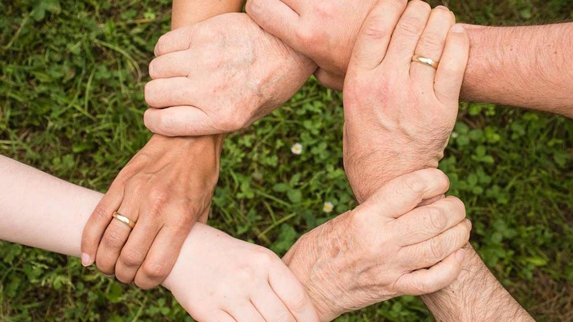 Sechs Hände bilden einen festen Kreis.